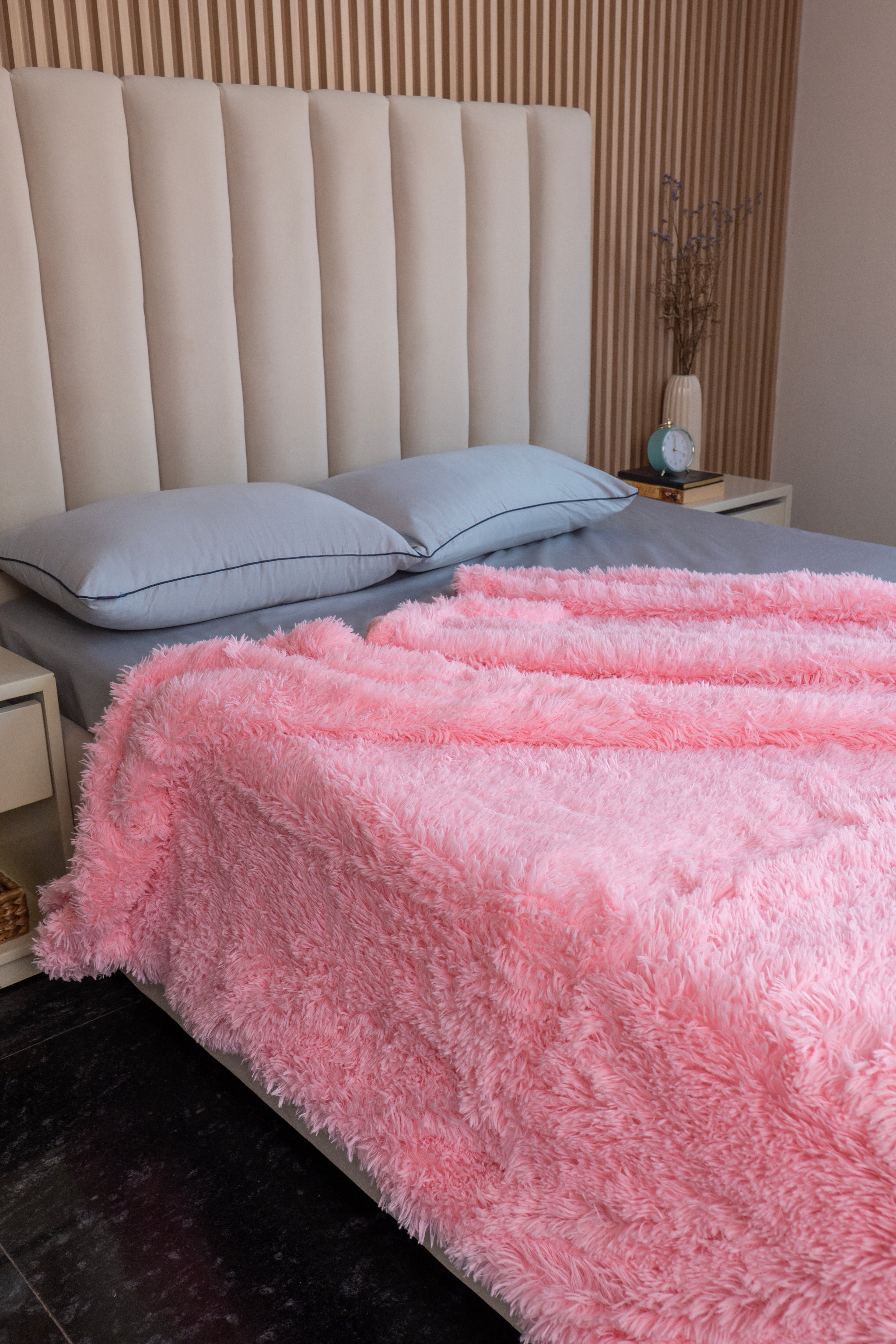 Featherlight Signature faux-fur blanket in baby pink, draped over a bed